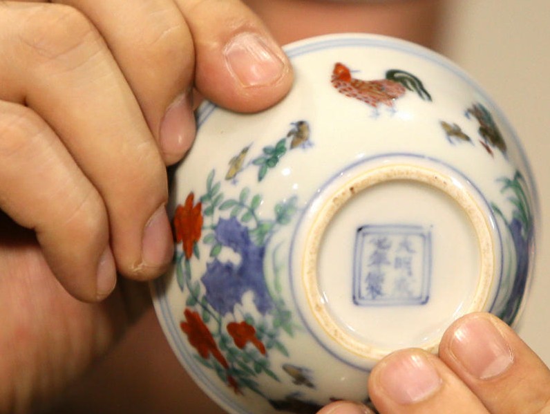 苏富比亚洲区副主席仇国仕在拍卖结束后向记者展示成交的明成化斗彩鸡缸杯。