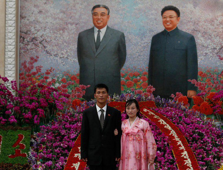 图为2012年4月17日，一对夫妇在金正日和金日成肖像前合影。