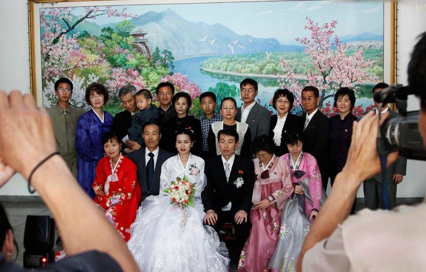 图为新婚夫妇在朝鲜平壤万寿台金日成铜像前合影。