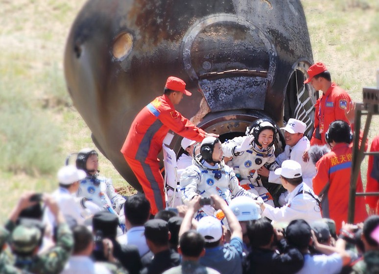 图为2012年6月29日，神九飞船成功着陆 ，航天员刘洋出舱后向现场工作人员挥手致意。